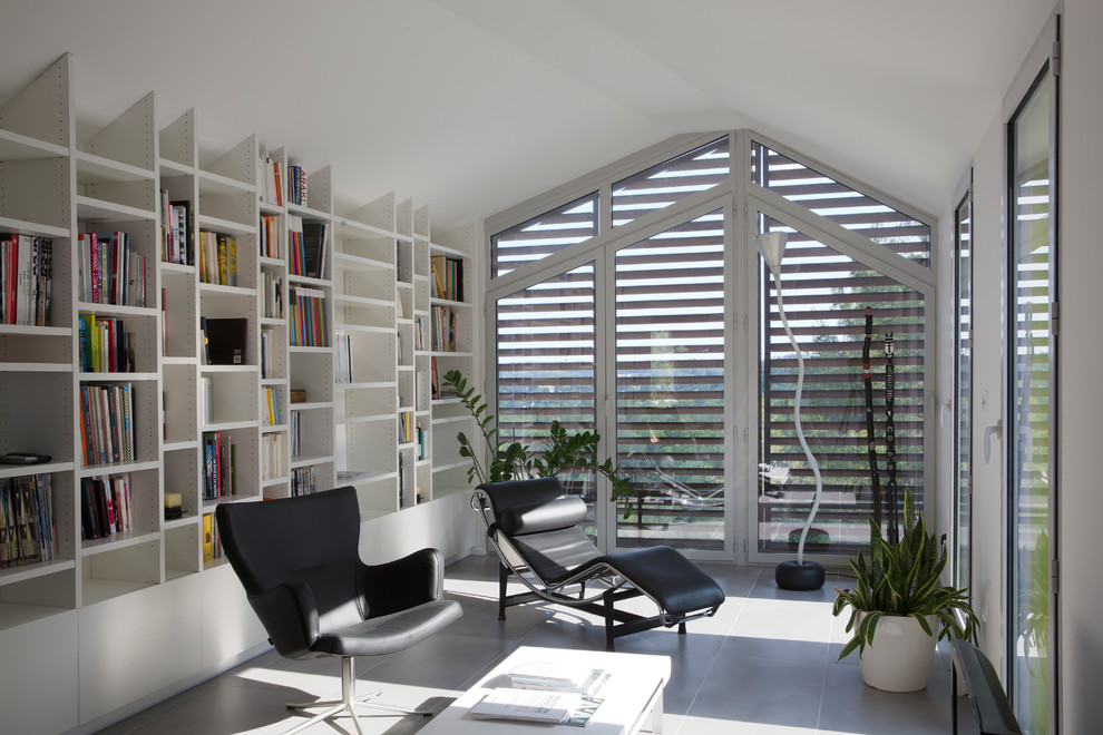 Aménagement d'une salle de séjour contemporaine avec une bibliothèque ou un coin lecture et un mur blanc.
