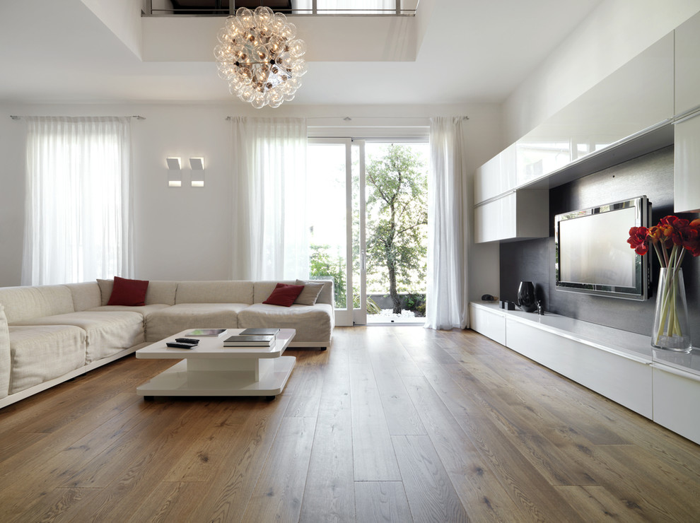 Ejemplo de sala de estar abierta moderna grande sin chimenea con paredes blancas, suelo de madera en tonos medios y televisor colgado en la pared