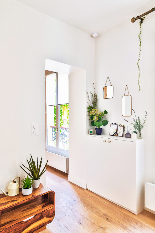 Mittelgroßes, Offenes Shabby-Style Wohnzimmer ohne Kamin mit Hausbar, weißer Wandfarbe, hellem Holzboden und freistehendem TV in Paris