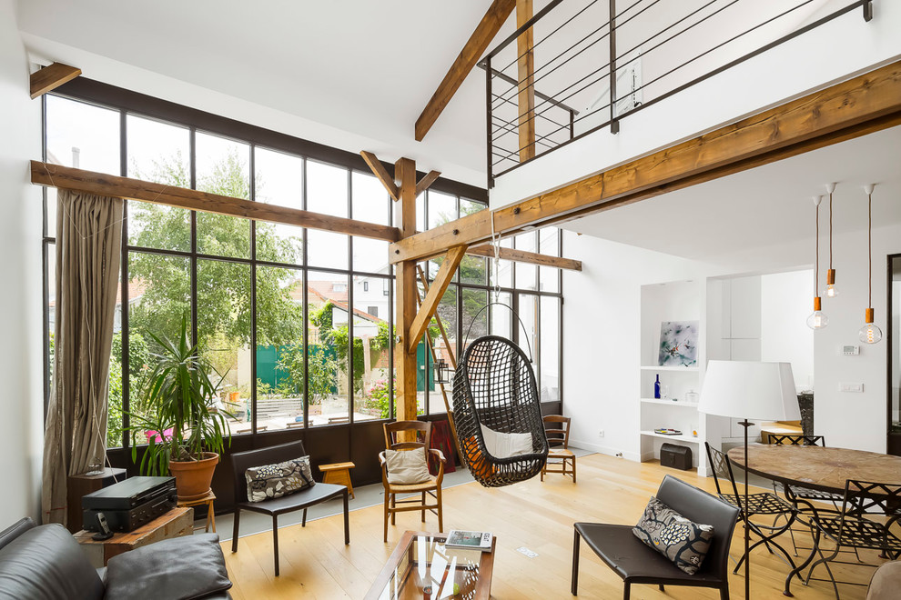 Ejemplo de sala de estar abierta urbana de tamaño medio sin chimenea y televisor con paredes blancas y suelo de madera clara