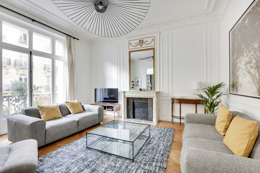 This is an example of a large contemporary open plan games room in Paris with white walls, light hardwood flooring, a standard fireplace, a stone fireplace surround, a freestanding tv and beige floors.
