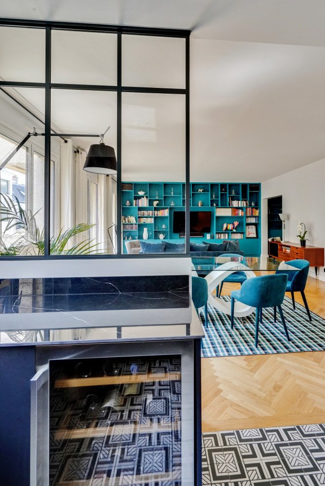 Diseño de sala de estar con biblioteca abierta actual grande sin chimenea con paredes azules, suelo de madera clara, televisor colgado en la pared y suelo beige