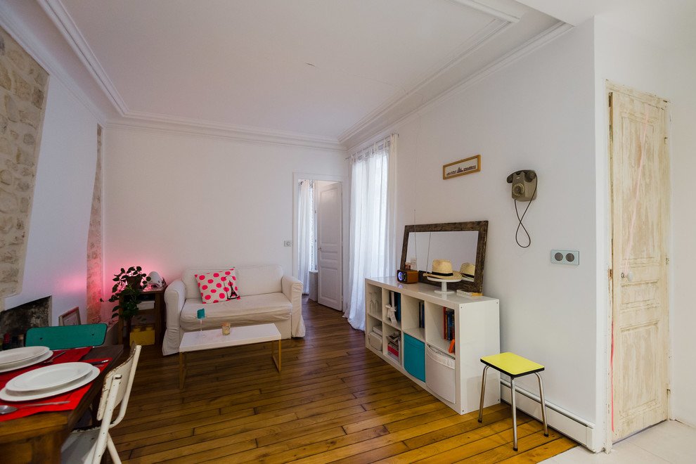 Offenes Nordisches Wohnzimmer mit weißer Wandfarbe, braunem Holzboden, Kaminofen und Kaminumrandung aus Backstein in Paris