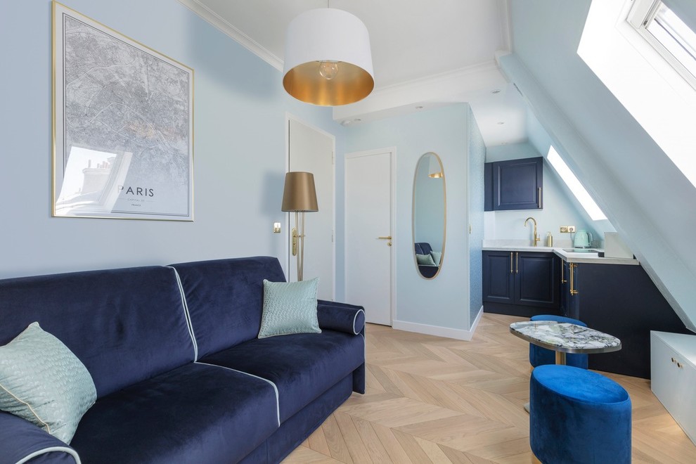 Diseño de sala de estar tipo loft clásica renovada pequeña con paredes azules, suelo de madera clara y televisor colgado en la pared