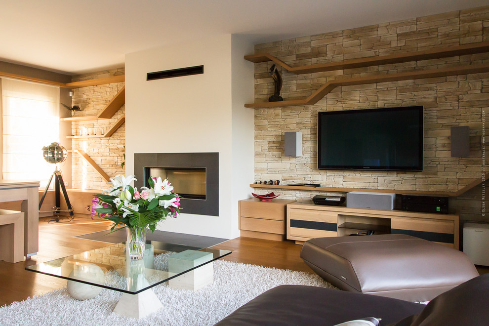 Imagen de sala de estar abierta contemporánea grande con paredes beige, suelo de madera en tonos medios, todas las chimeneas, marco de chimenea de baldosas y/o azulejos y televisor colgado en la pared