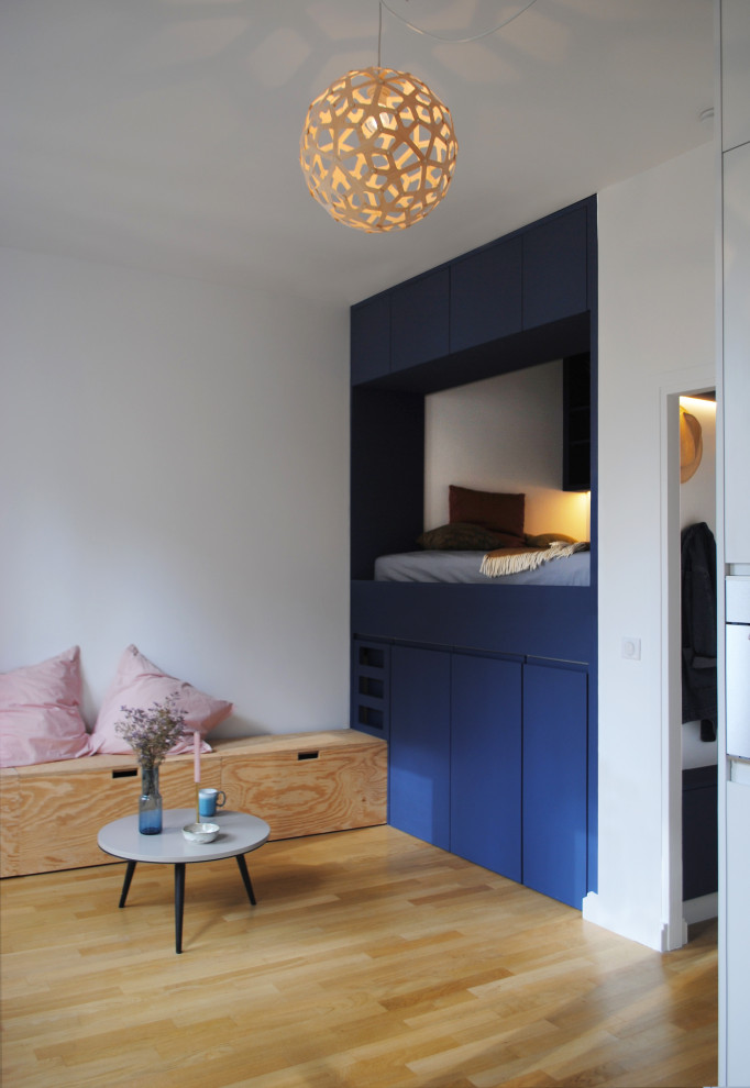 Réalisation d'une petite salle de séjour design ouverte avec un mur blanc, parquet clair et un sol beige.