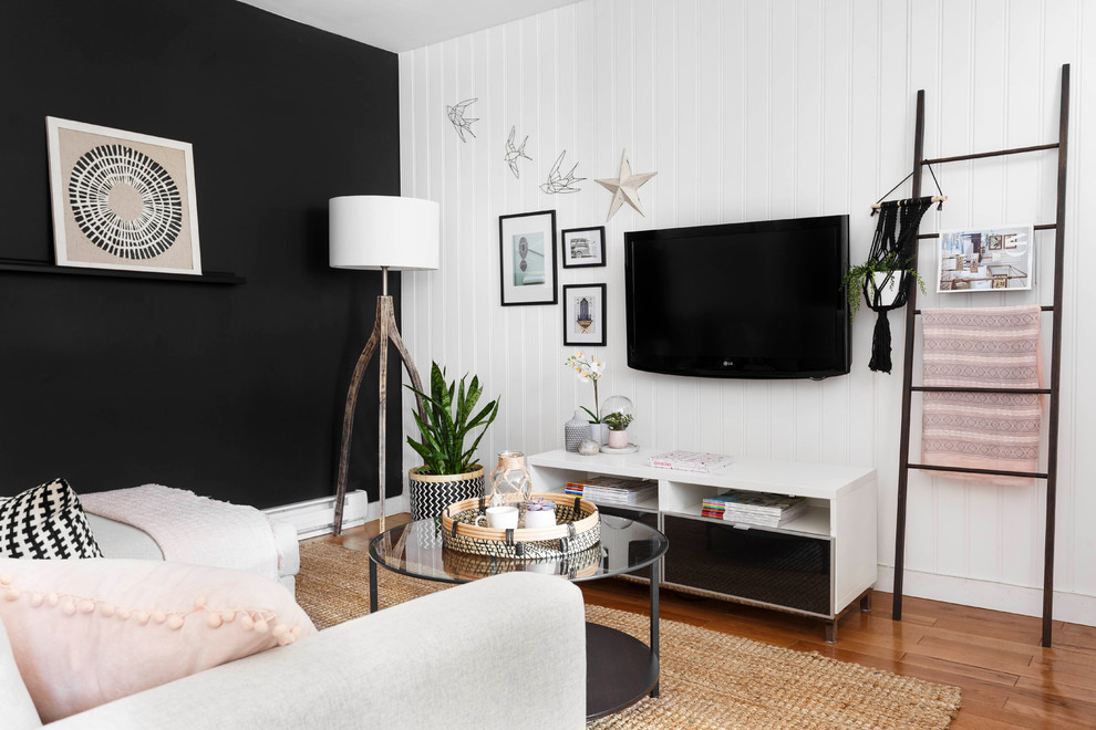 Family room - small scandinavian medium tone wood floor family room idea in Montreal with black walls, a wall-mounted tv and no fireplace
