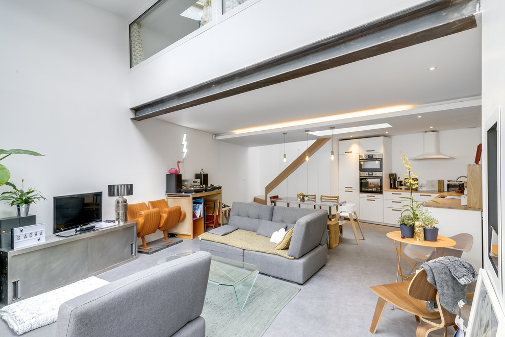 Geräumiges, Offenes Modernes Wohnzimmer ohne Kamin mit weißer Wandfarbe, Vinylboden, freistehendem TV und grauem Boden in Paris