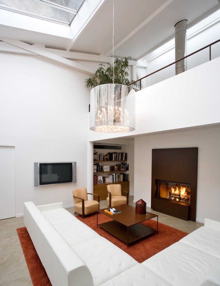Идея дизайна: большая открытая гостиная комната в современном стиле с белыми стенами, стандартным камином, телевизором на стене, бетонным полом и фасадом камина из металла