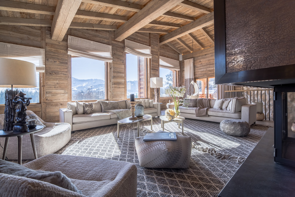 Imagen de sala de estar abierta rústica grande con paredes beige, suelo de madera en tonos medios, chimenea de doble cara y marco de chimenea de metal