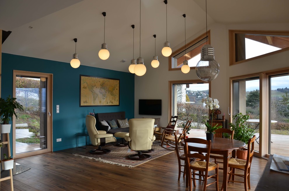 Источник вдохновения для домашнего уюта: большая открытая гостиная комната в стиле неоклассика (современная классика) с синими стенами, паркетным полом среднего тона, печью-буржуйкой, телевизором на стене и коричневым полом
