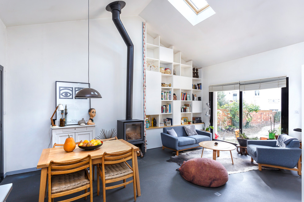 Imagen de sala de estar con biblioteca tipo loft escandinava pequeña sin televisor con paredes blancas, suelo vinílico, estufa de leña y suelo gris
