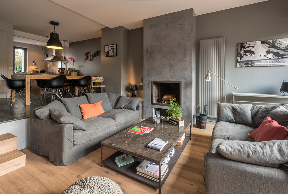 Idées déco pour une salle de séjour moderne de taille moyenne et ouverte avec un mur gris, un sol en bois brun, une cheminée ribbon, un manteau de cheminée en plâtre et un sol marron.