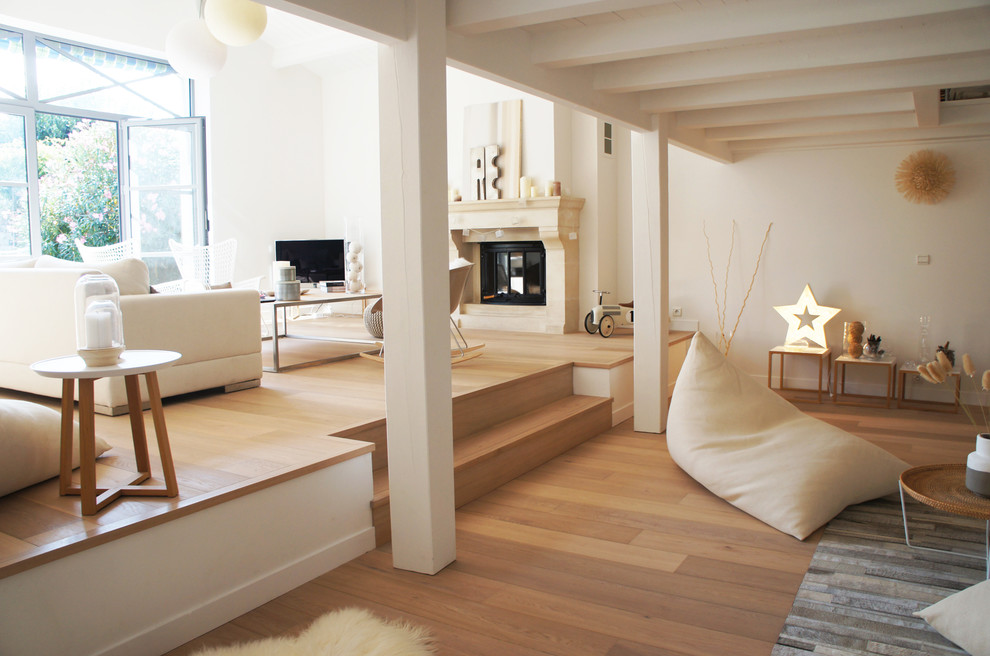 Inspiration pour une grande salle de séjour design ouverte avec un mur blanc, un sol en bois brun, une cheminée standard, un manteau de cheminée en pierre et un téléviseur indépendant.