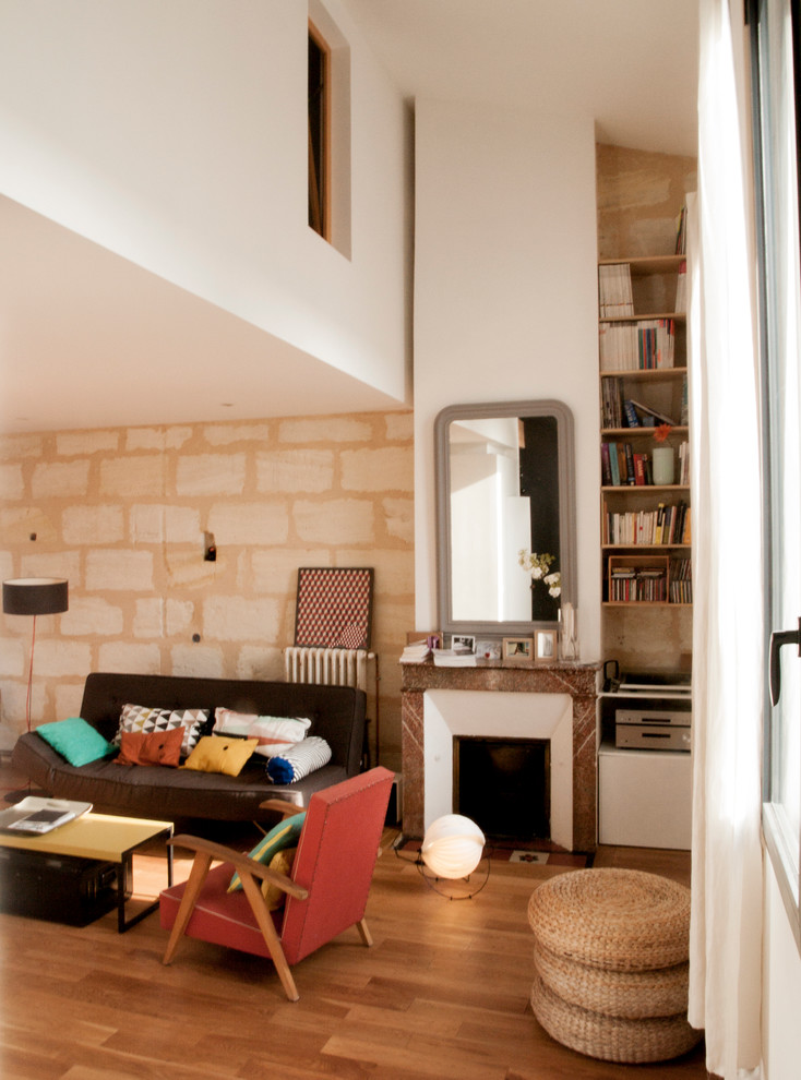Réalisation d'une salle de séjour design de taille moyenne et ouverte avec une bibliothèque ou un coin lecture, un mur beige, un sol en bois brun, une cheminée standard et un manteau de cheminée en pierre.