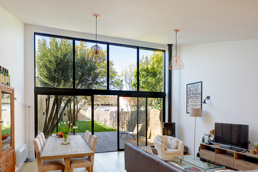 Mittelgroßes, Offenes Modernes Wohnzimmer mit weißer Wandfarbe, braunem Holzboden und freistehendem TV in Bordeaux