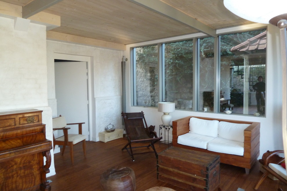Cette photo montre une grande salle de séjour exotique ouverte avec un mur blanc, un sol en bois brun, aucune cheminée et un sol marron.