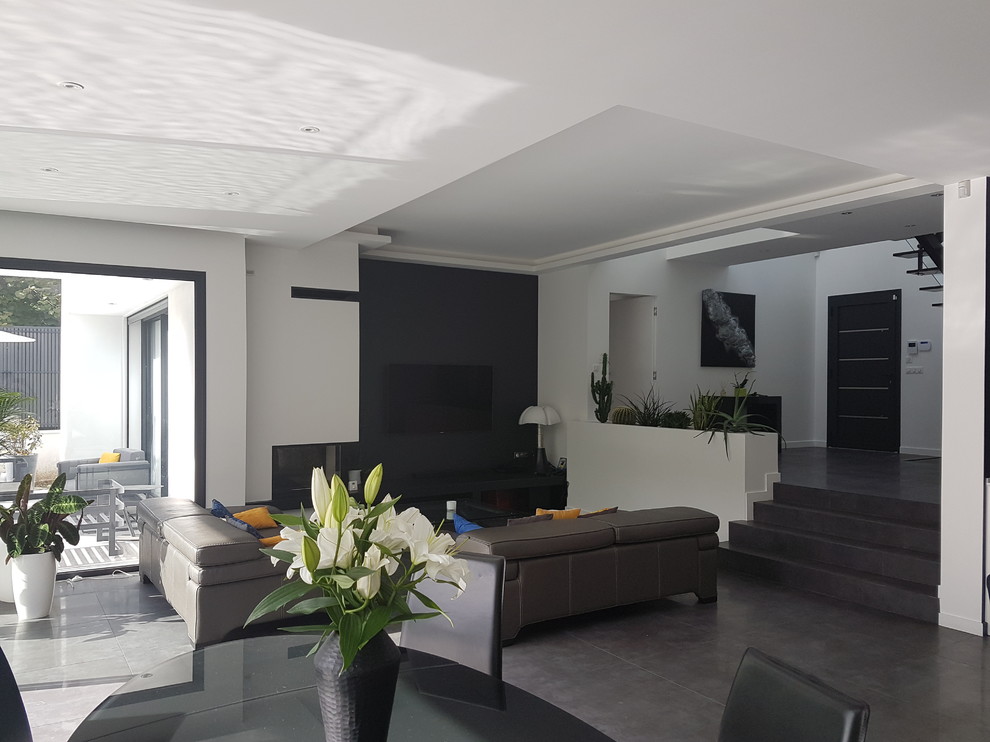 Immagine di un grande soggiorno moderno aperto con pareti bianche, pavimento con piastrelle in ceramica, camino ad angolo, TV nascosta e pavimento nero