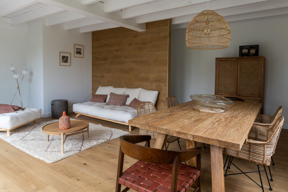 Imagen de sala de estar abierta bohemia extra grande sin televisor con paredes beige, suelo de madera clara, suelo beige y vigas vistas