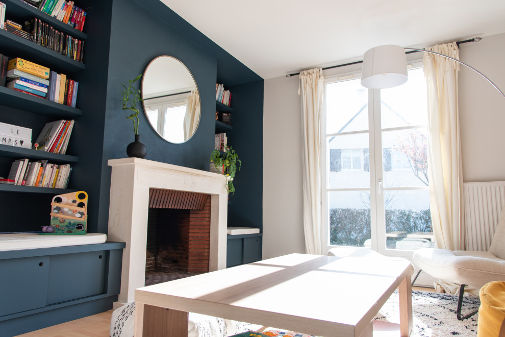 Idée de décoration pour une salle de séjour minimaliste de taille moyenne et ouverte avec salle de jeu, un mur bleu, parquet clair, une cheminée standard, un manteau de cheminée en pierre, aucun téléviseur et un sol marron.