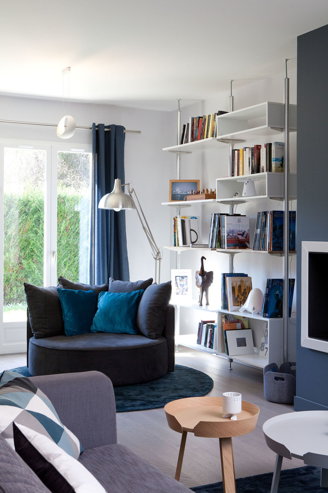 Foto de sala de estar con biblioteca abierta actual de tamaño medio con suelo de madera clara, paredes blancas y suelo gris
