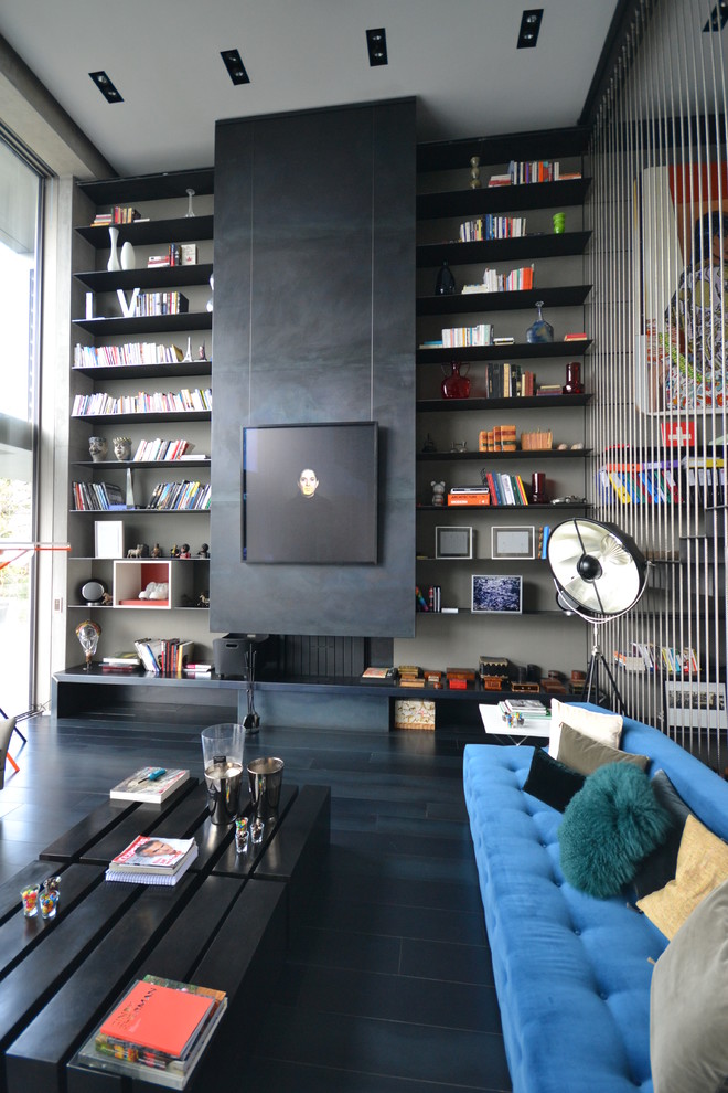 На фото: открытая гостиная комната среднего размера в современном стиле с с книжными шкафами и полками, черными стенами и стандартным камином без телевизора