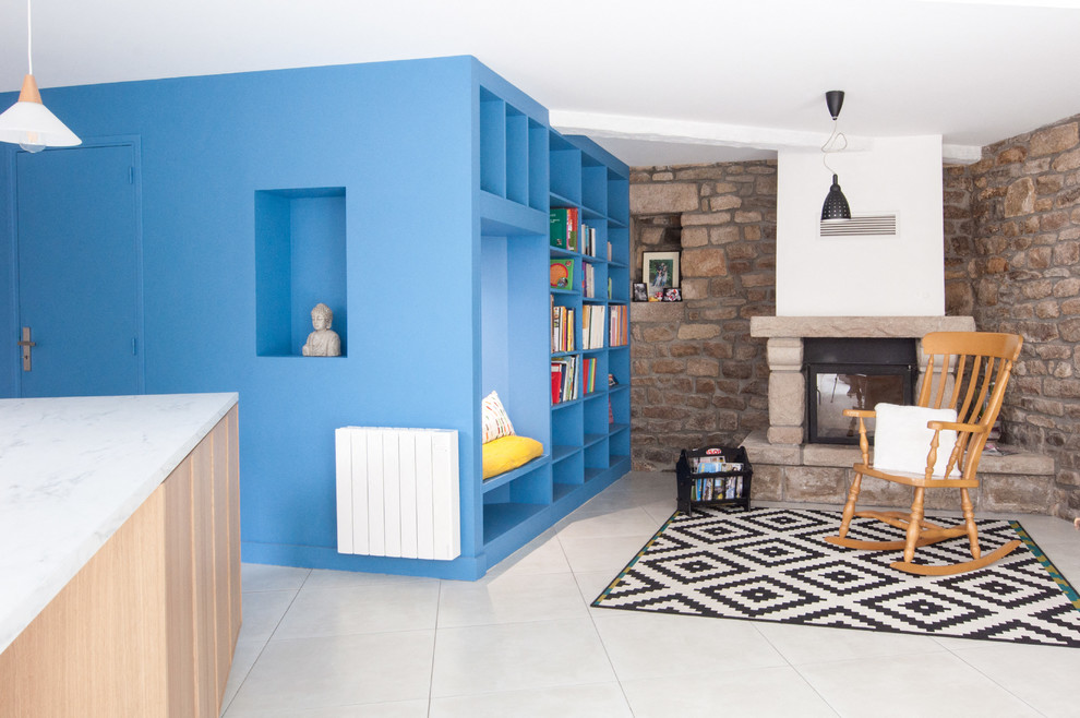 Cette photo montre une salle de séjour éclectique ouverte et de taille moyenne avec une bibliothèque ou un coin lecture, un mur bleu, un sol en carrelage de céramique, une cheminée standard et un manteau de cheminée en pierre.