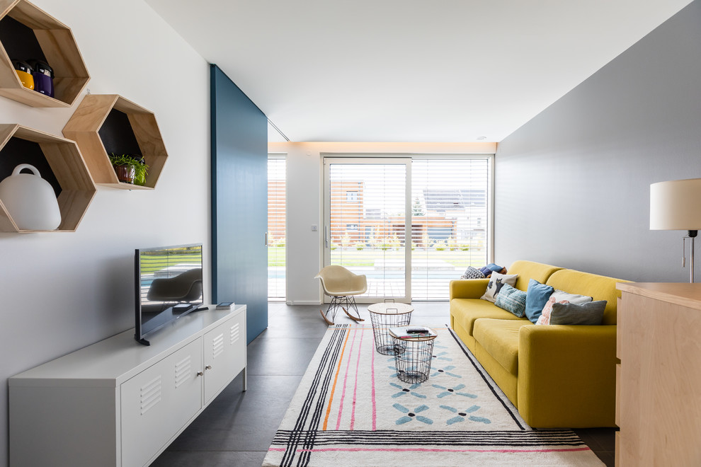 Cette image montre une salle de séjour design de taille moyenne et ouverte avec un mur bleu, un sol en carrelage de céramique, un téléviseur indépendant et un sol gris.