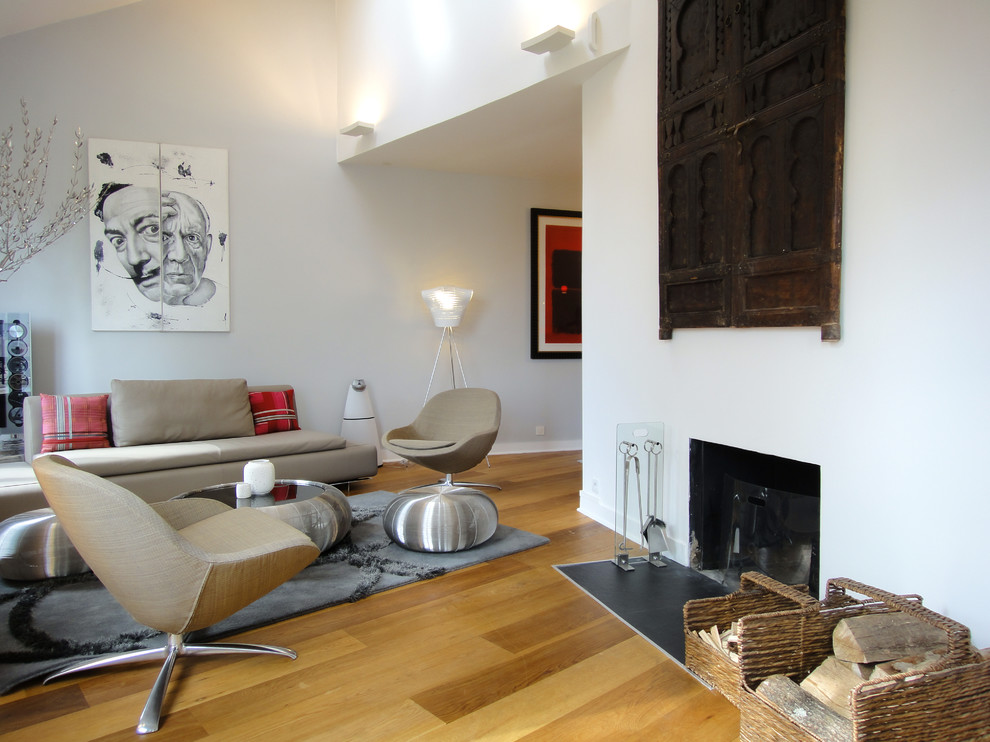 Exemple d'une salle de séjour éclectique ouverte et de taille moyenne avec un mur blanc, parquet clair, une cheminée standard et un manteau de cheminée en plâtre.