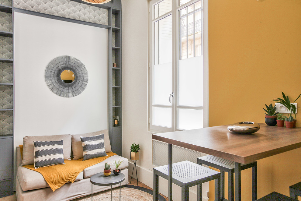 パリにある高級な中くらいなインダストリアルスタイルのおしゃれなロフトリビング (黄色い壁、無垢フローリング、暖炉なし、茶色い床、ライブラリー、壁掛け型テレビ) の写真