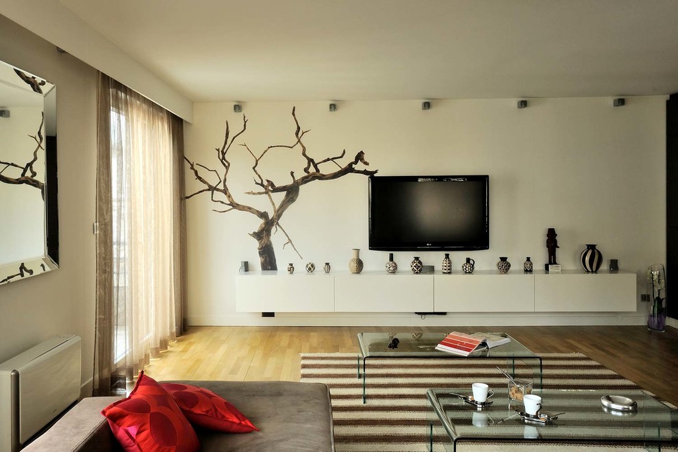 Imagen de sala de estar cerrada, actual, de tamaño medio, sin chimenea, con paredes blancas, suelo de madera clara y televisor colgado en la pared