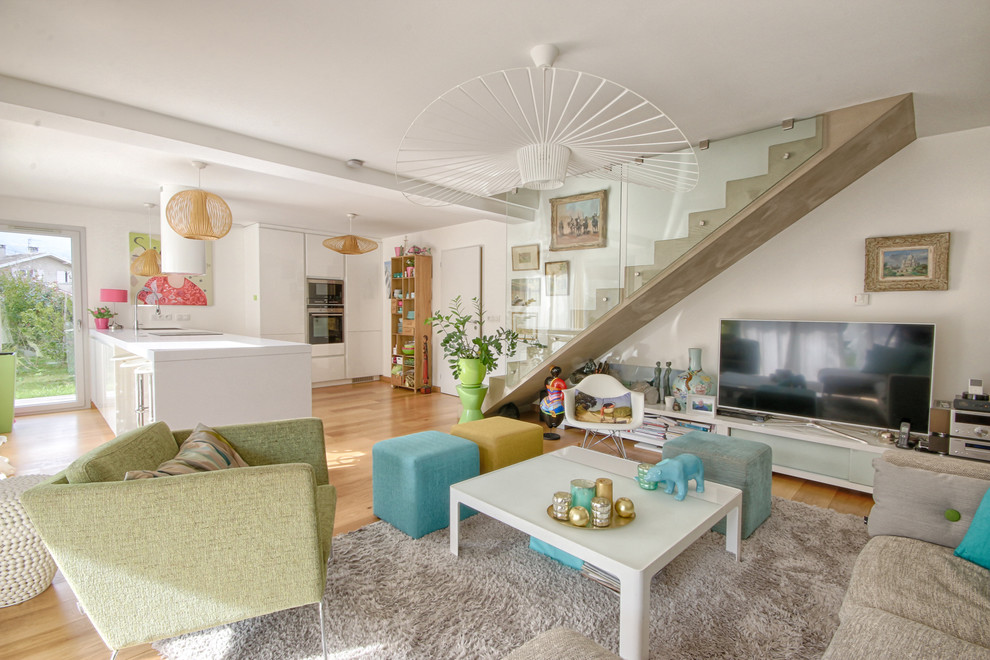 Foto de sala de estar abierta contemporánea de tamaño medio sin chimenea con suelo de madera clara, televisor independiente y paredes blancas