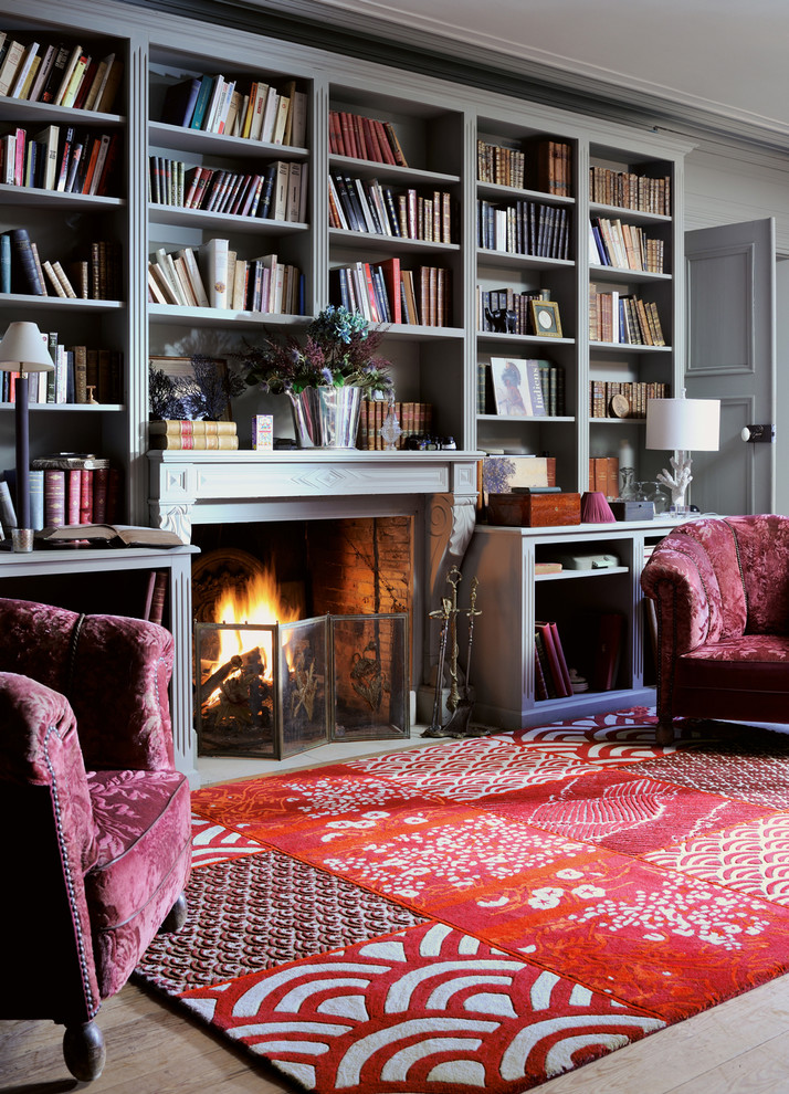 Ejemplo de sala de estar con biblioteca cerrada tradicional de tamaño medio con paredes grises, suelo de madera clara y todas las chimeneas