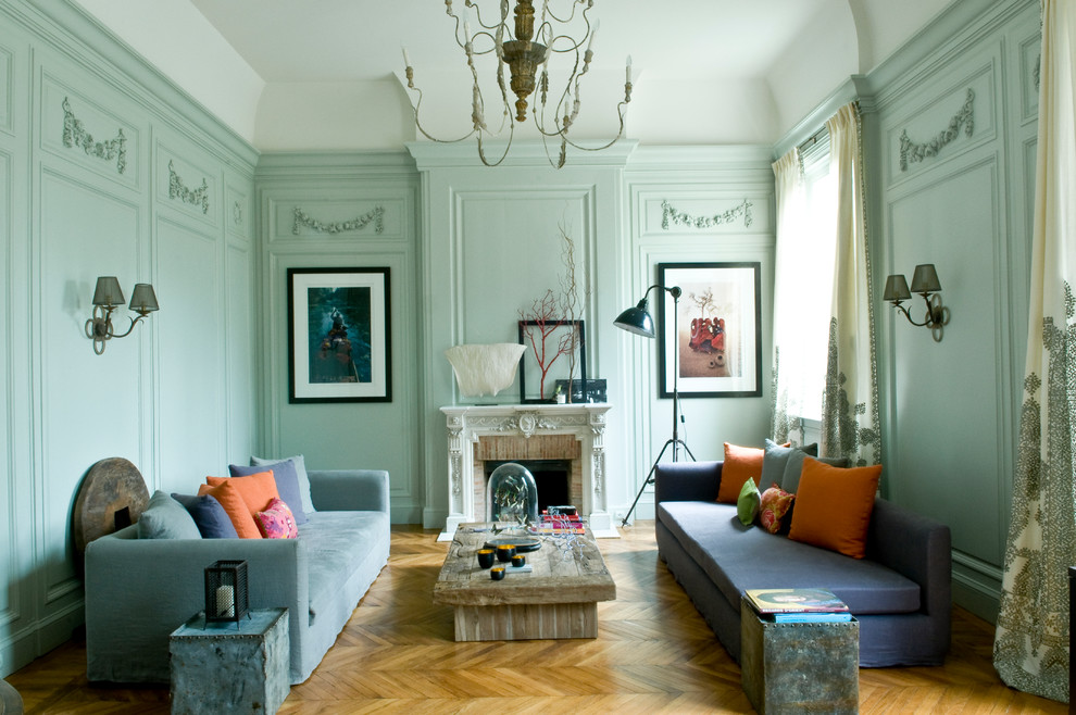 パリにある高級な広いエクレクティックスタイルのおしゃれな独立型ファミリールーム (青い壁、無垢フローリング、テレビなし、標準型暖炉、石材の暖炉まわり、ベージュの床) の写真