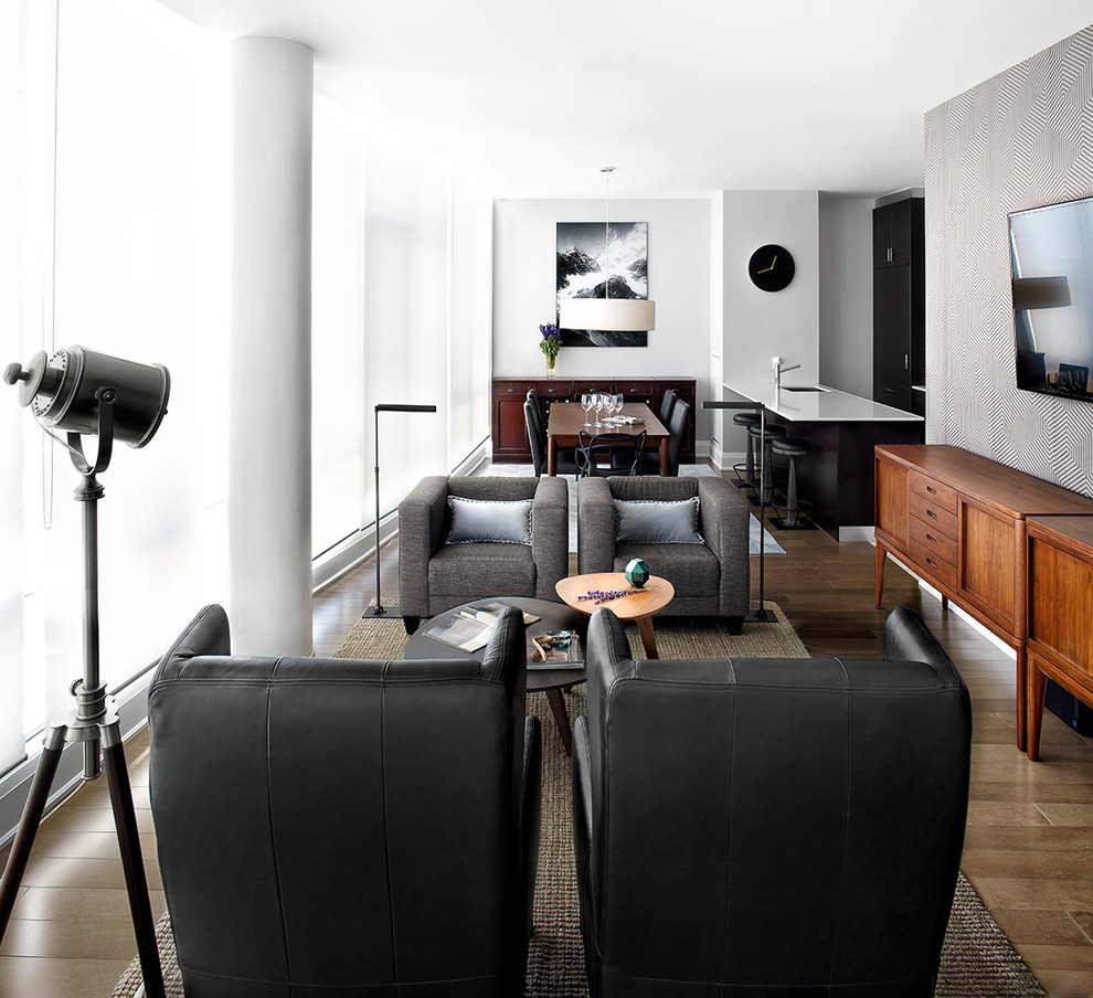 Cette photo montre une salle de séjour moderne de taille moyenne et ouverte avec un mur gris, un sol en bois brun et un téléviseur fixé au mur.