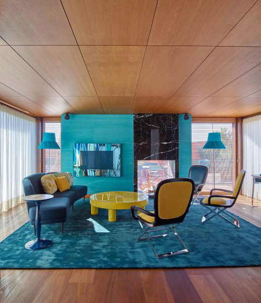 Esempio di un soggiorno design con pareti blu, pavimento in legno massello medio, camino bifacciale, cornice del camino in pietra e TV nascosta