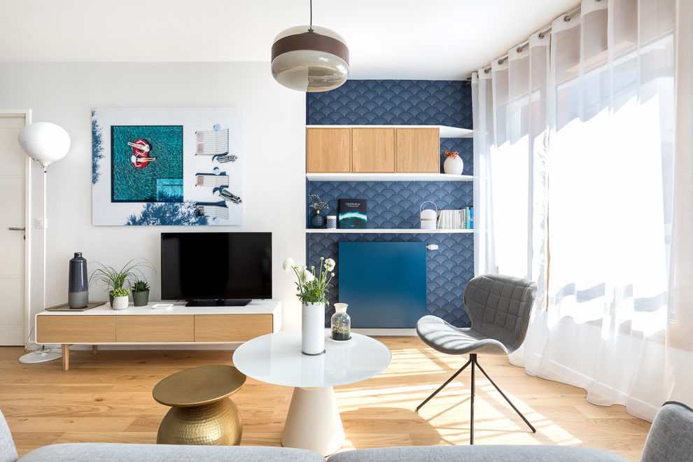 Foto de sala de estar abierta costera de tamaño medio sin chimenea con paredes blancas, suelo de madera clara, televisor independiente y suelo beige