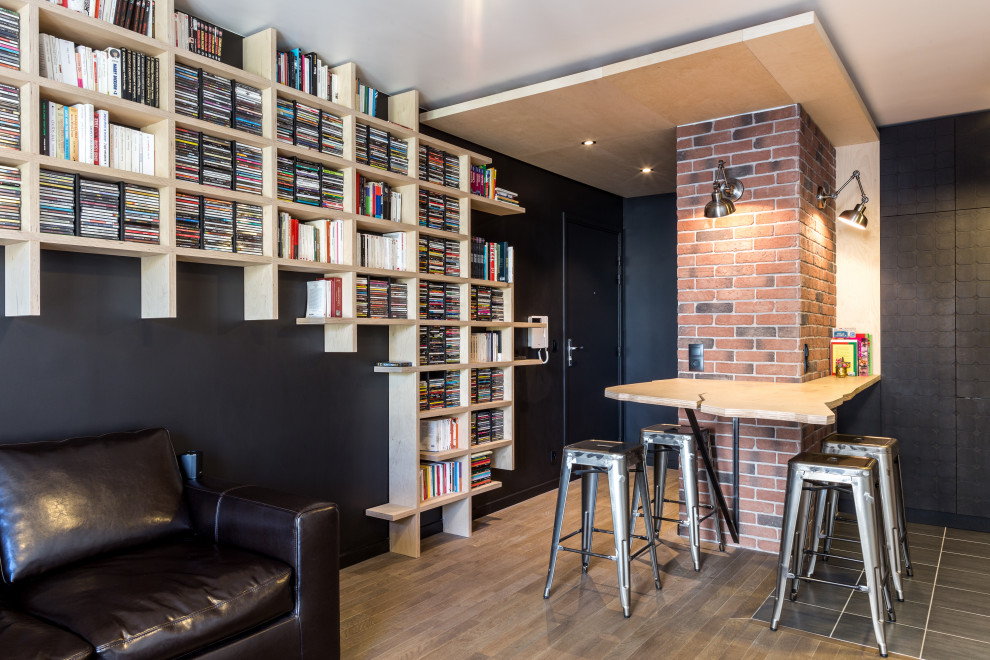 Cette image montre une petite salle de séjour design ouverte avec une bibliothèque ou un coin lecture, un mur noir, sol en stratifié, aucune cheminée, aucun téléviseur et un sol beige.