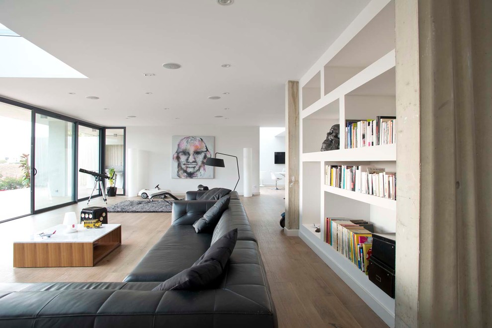 Modelo de sala de estar con biblioteca abierta actual extra grande con paredes blancas y suelo de madera en tonos medios