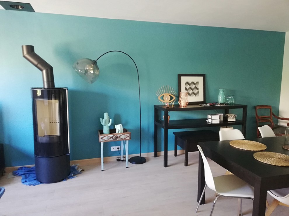 Modelo de sala de estar abierta bohemia de tamaño medio con paredes azules, suelo laminado, estufa de leña y televisor independiente