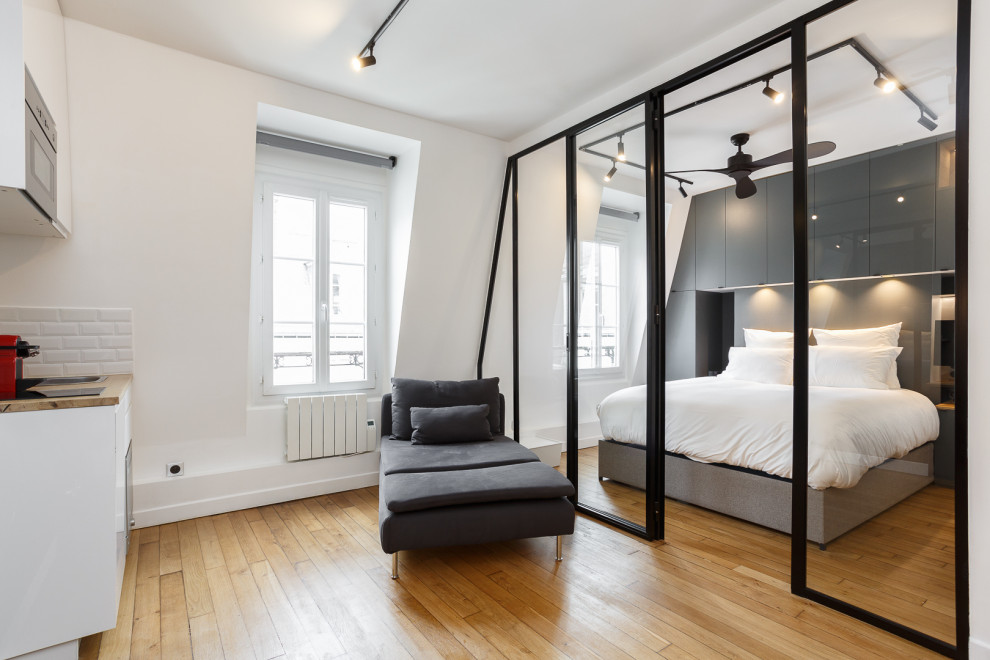 パリにあるお手頃価格の小さなインダストリアルスタイルのおしゃれなオープンリビング (ライブラリー、白い壁、淡色無垢フローリング、暖炉なし、壁掛け型テレビ、ベージュの床) の写真