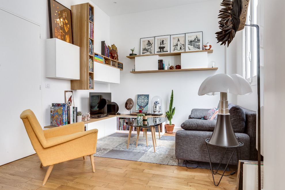 Пример оригинального дизайна: изолированная гостиная комната в стиле фьюжн с с книжными шкафами и полками, белыми стенами, паркетным полом среднего тона, отдельно стоящим телевизором и коричневым полом