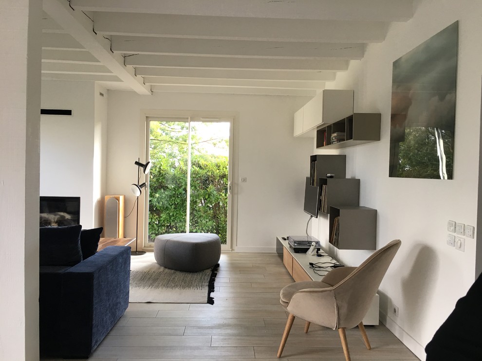 Photo of a large scandinavian open plan games room in Bordeaux with white walls, light hardwood flooring, no fireplace, a wall mounted tv and beige floors.