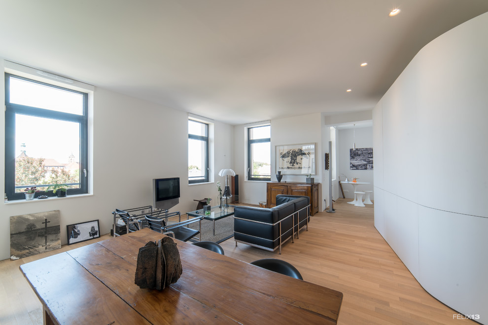 Ejemplo de sala de estar abierta actual de tamaño medio con paredes blancas y suelo de madera clara