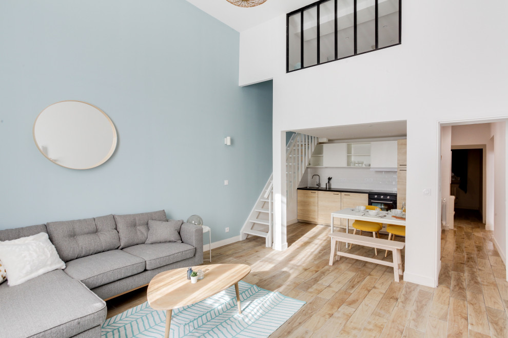 Идея дизайна: большая двухуровневая гостиная комната в скандинавском стиле с синими стенами, светлым паркетным полом, коричневым полом и многоуровневым потолком