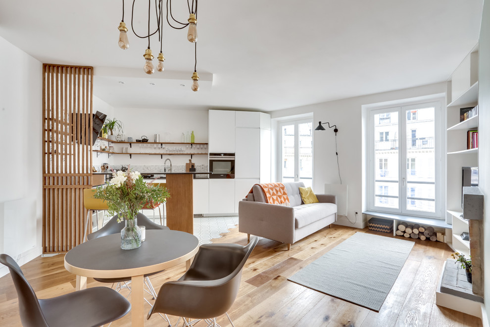Diseño de sala de estar abierta nórdica con paredes blancas, suelo de madera en tonos medios, todas las chimeneas, televisor independiente y suelo marrón