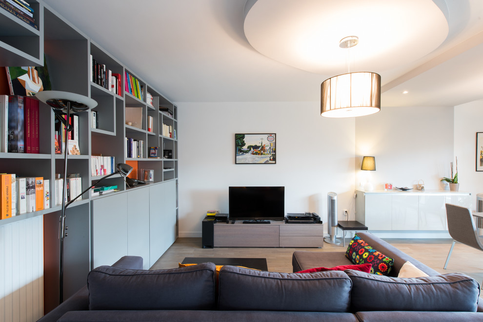 Idee per un grande soggiorno design aperto con libreria, pareti bianche, parquet chiaro e TV autoportante