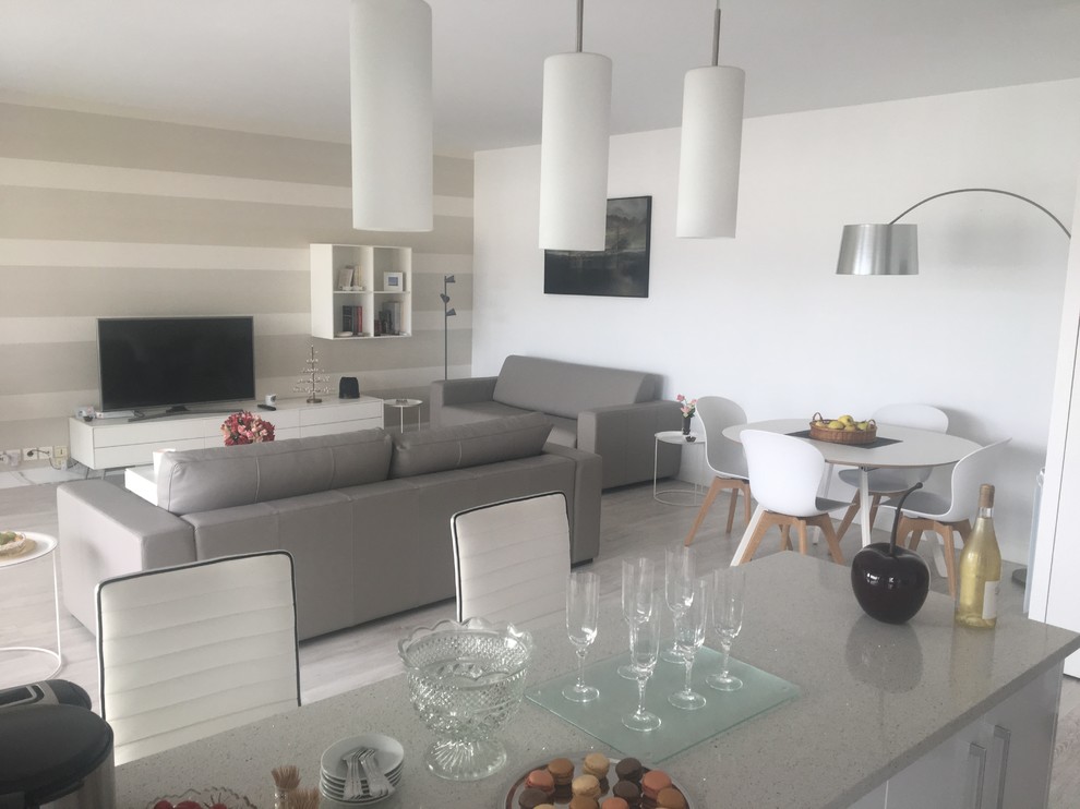 Medium sized beach style open plan games room in Bordeaux with beige walls, laminate floors, no fireplace, a freestanding tv and grey floors.