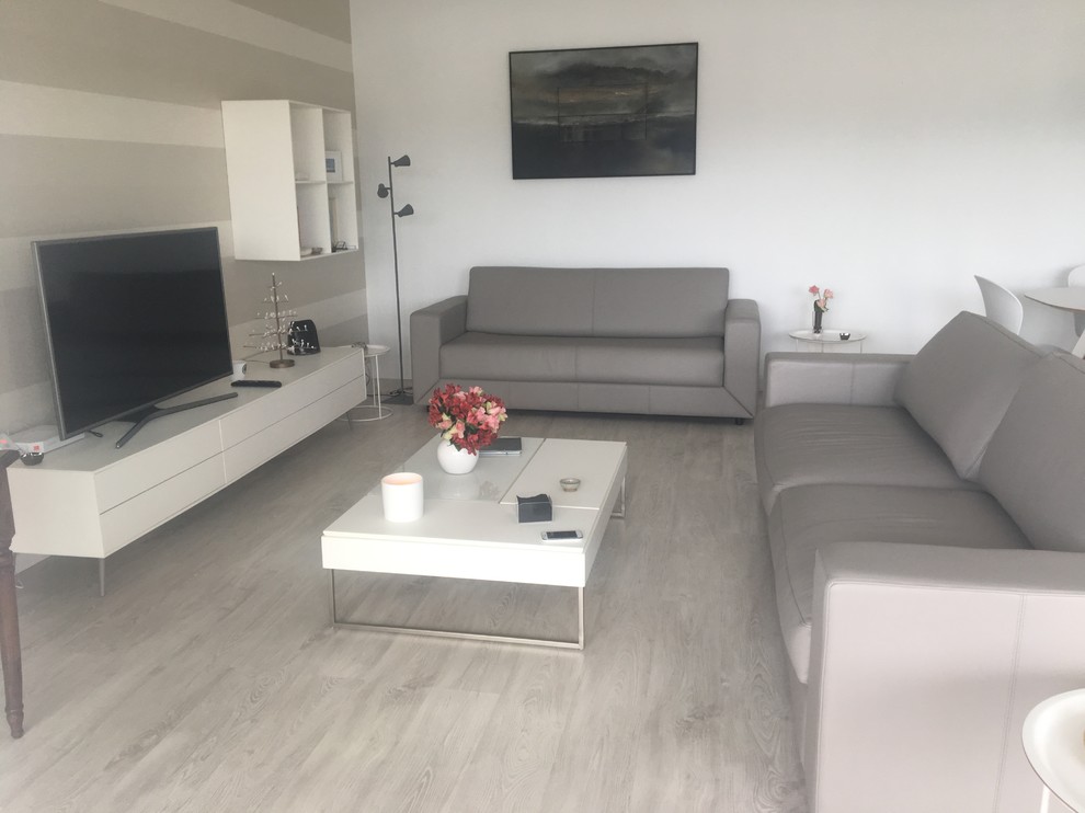 Imagen de sala de estar abierta marinera de tamaño medio sin chimenea con paredes beige, suelo laminado, televisor independiente y suelo gris