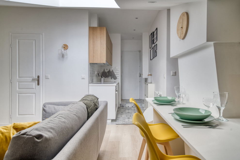 Diseño de sala de estar con biblioteca tipo loft escandinava pequeña con paredes amarillas, suelo de madera clara, todas las chimeneas, marco de chimenea de piedra, suelo marrón y bandeja